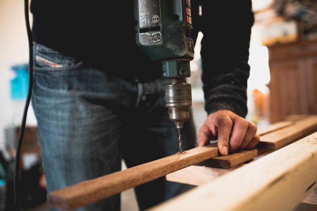 pexels-photo-1094767 Man Holding Wooden Stick While Drilling Hole